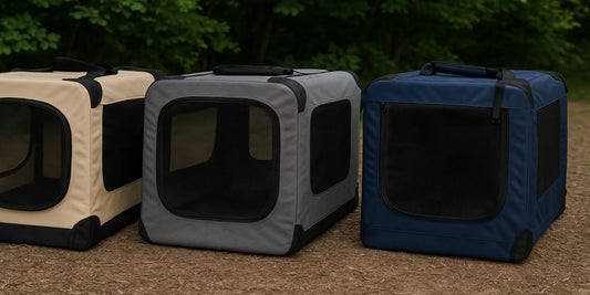 Three portable soft dog crates in beige, gray, and navy blue, with mesh windows, displayed outdoors on a dirt path with green foliage backdrop.